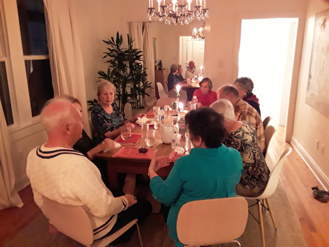 People sitting around tables with candlelight, sharing a meal.